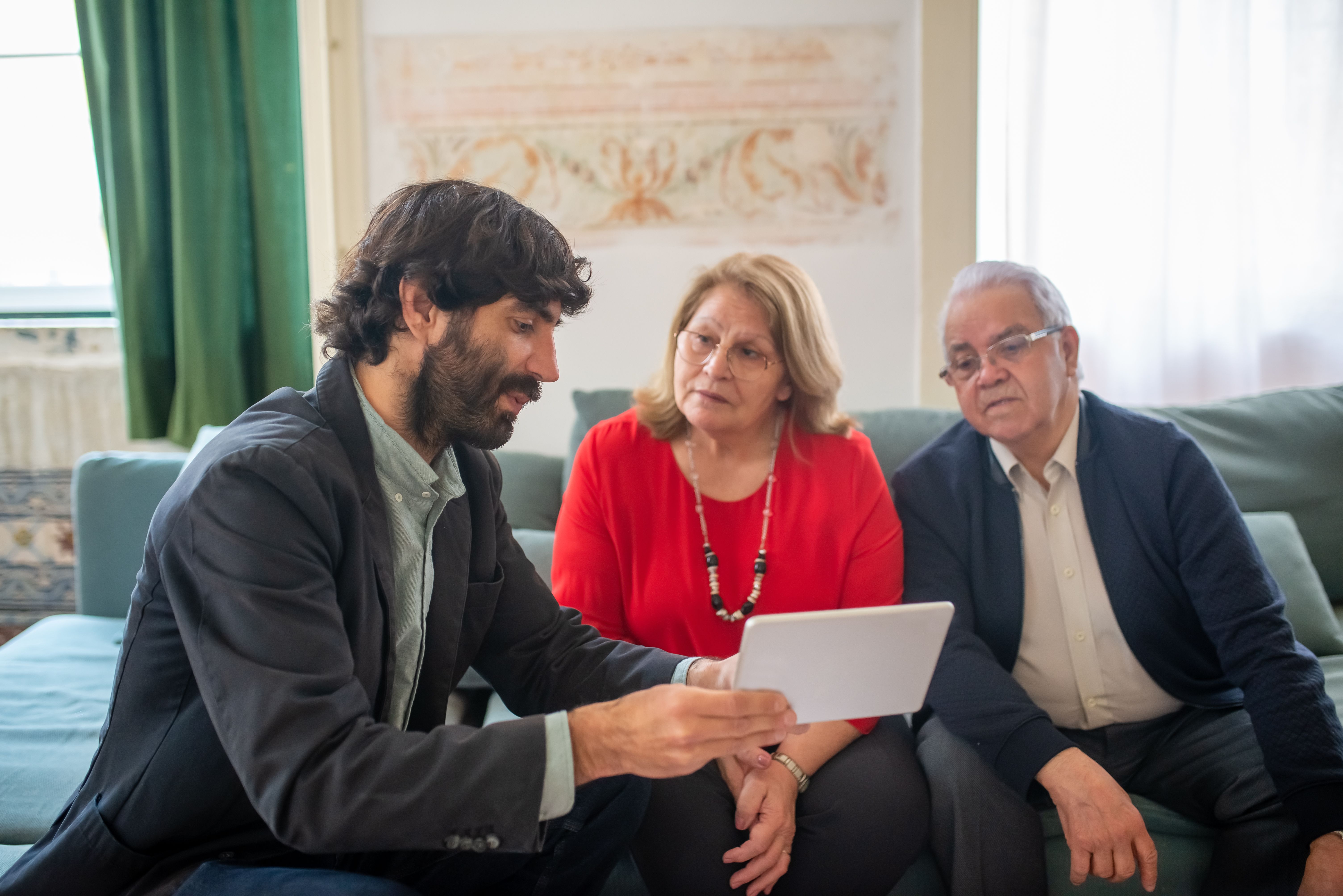 Financial advisor having an honest conversation with an elderly couple about their investments in a cozy living room