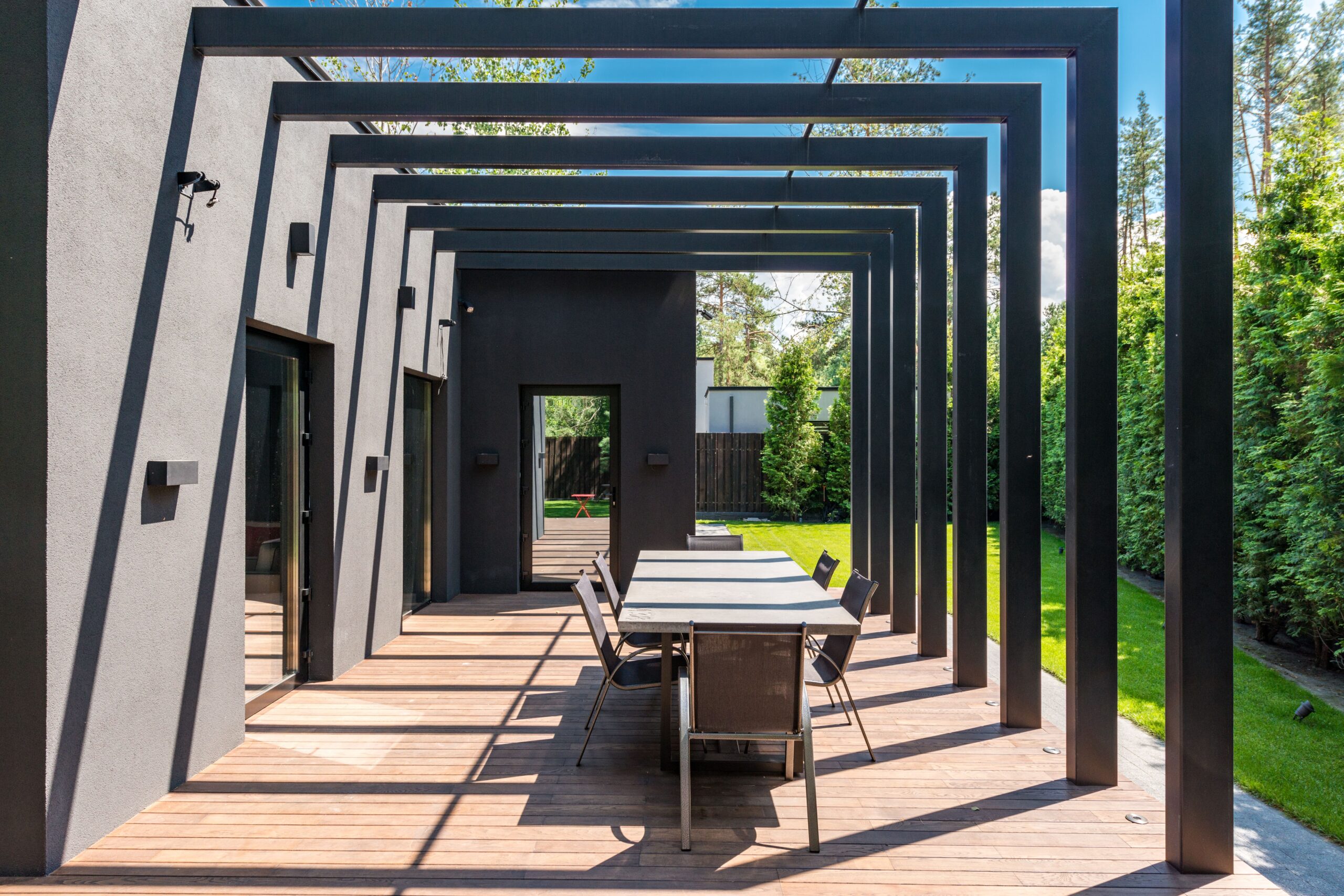 Contemporary backyard patio with a pergola and outdoor dining set, illustrating a lasting outdoor home improvement gift.